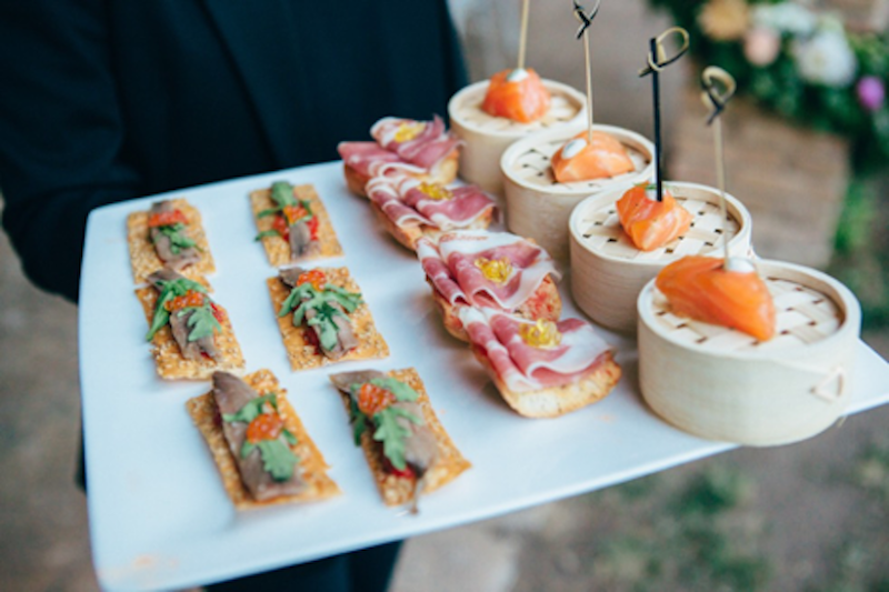 Tapas dishes in waiters hands including Iberico ham, salmon and coca bread with anchovy Tapas dishes in waiters hands including Iberico ham, salmon and coca bread with anchovy