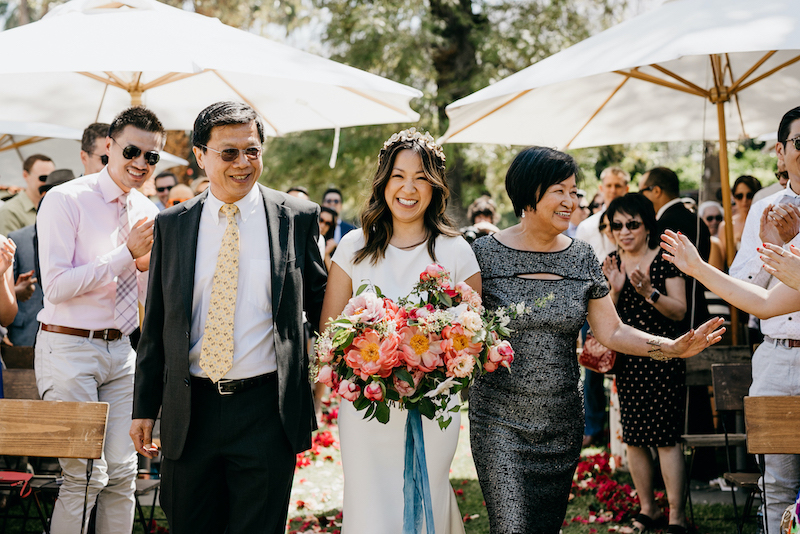 A bride walking down the aisle with both her mother and father