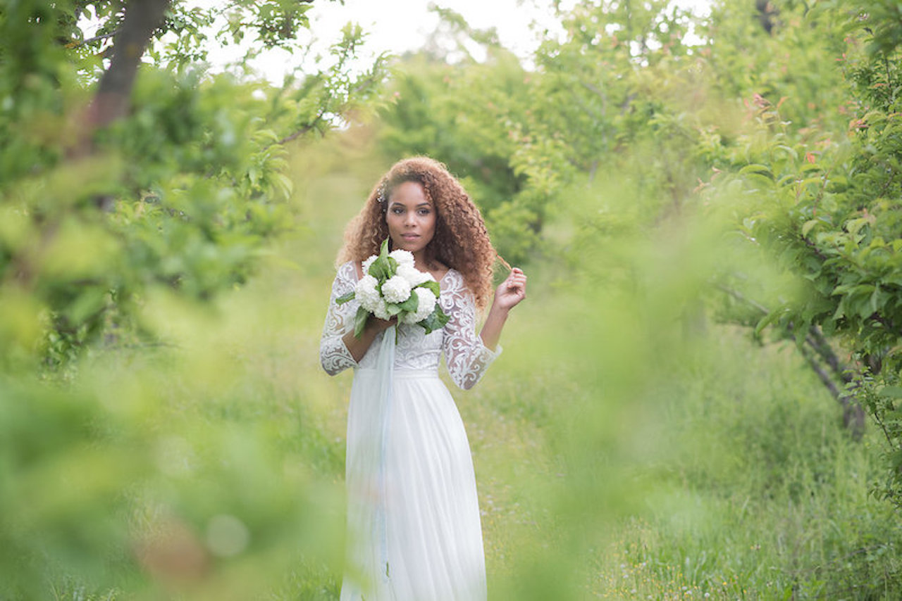 A bride outside in her bridal dress holding a wedding bouquet