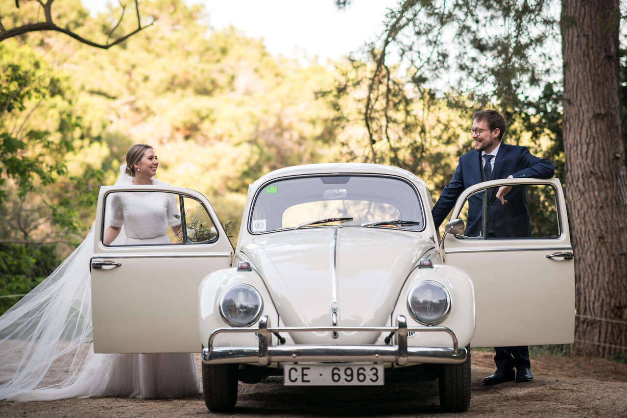 A bride and groom stood on either side of a car